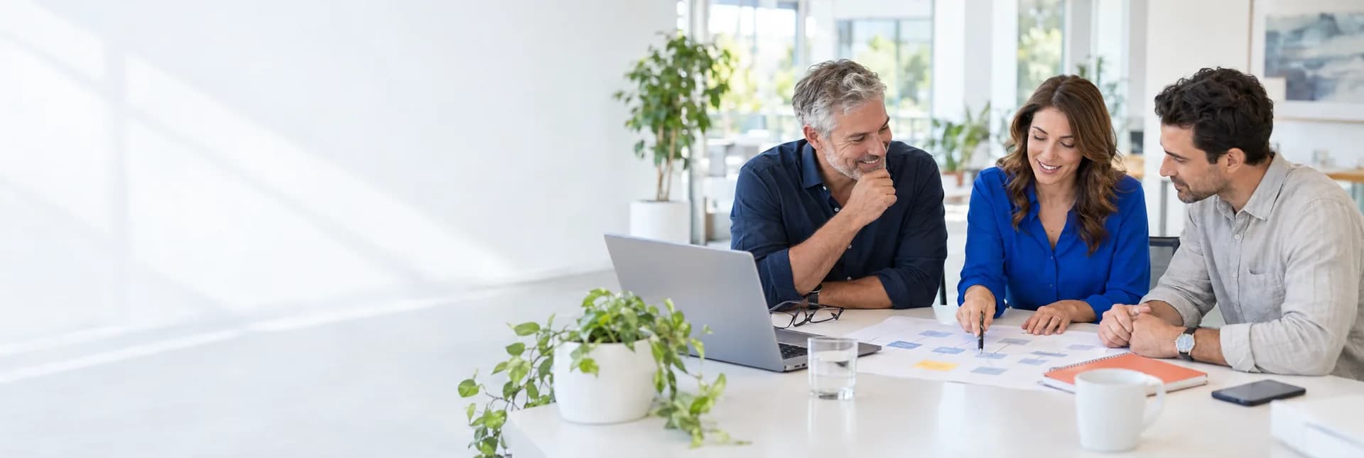 Illustrative AI consulting workshop: a business owner and colleagues review a workflow plan together in a bright white office.